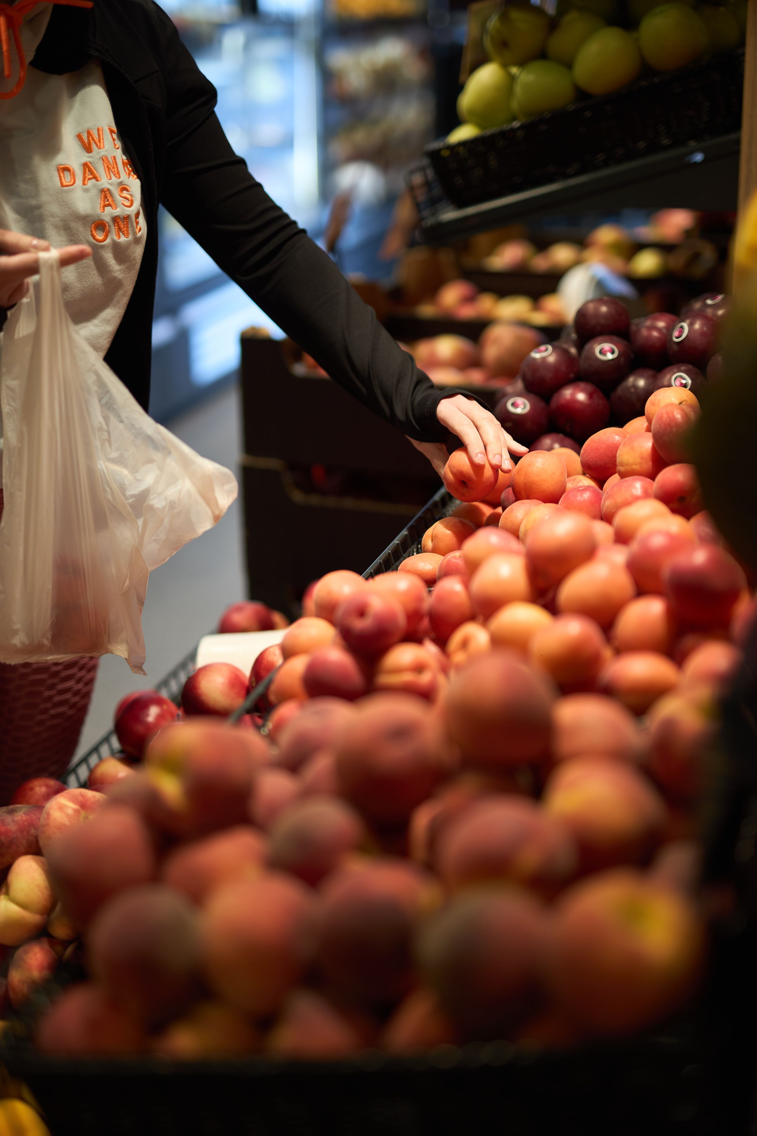 Fresh red apples arranged in retail produce display with hand selecting fruit.