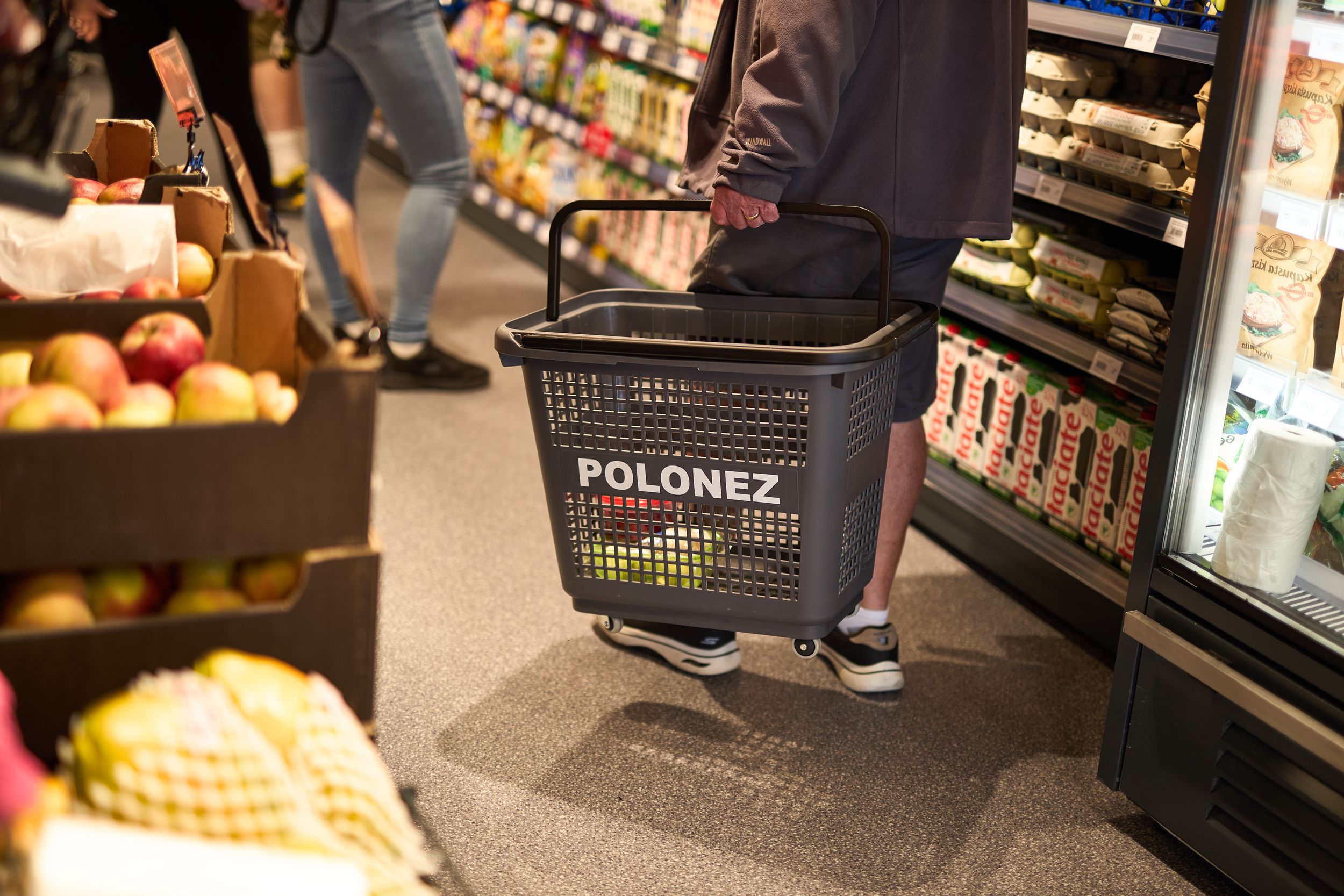 Shopping baskets and store shelving visible in retail environment.
