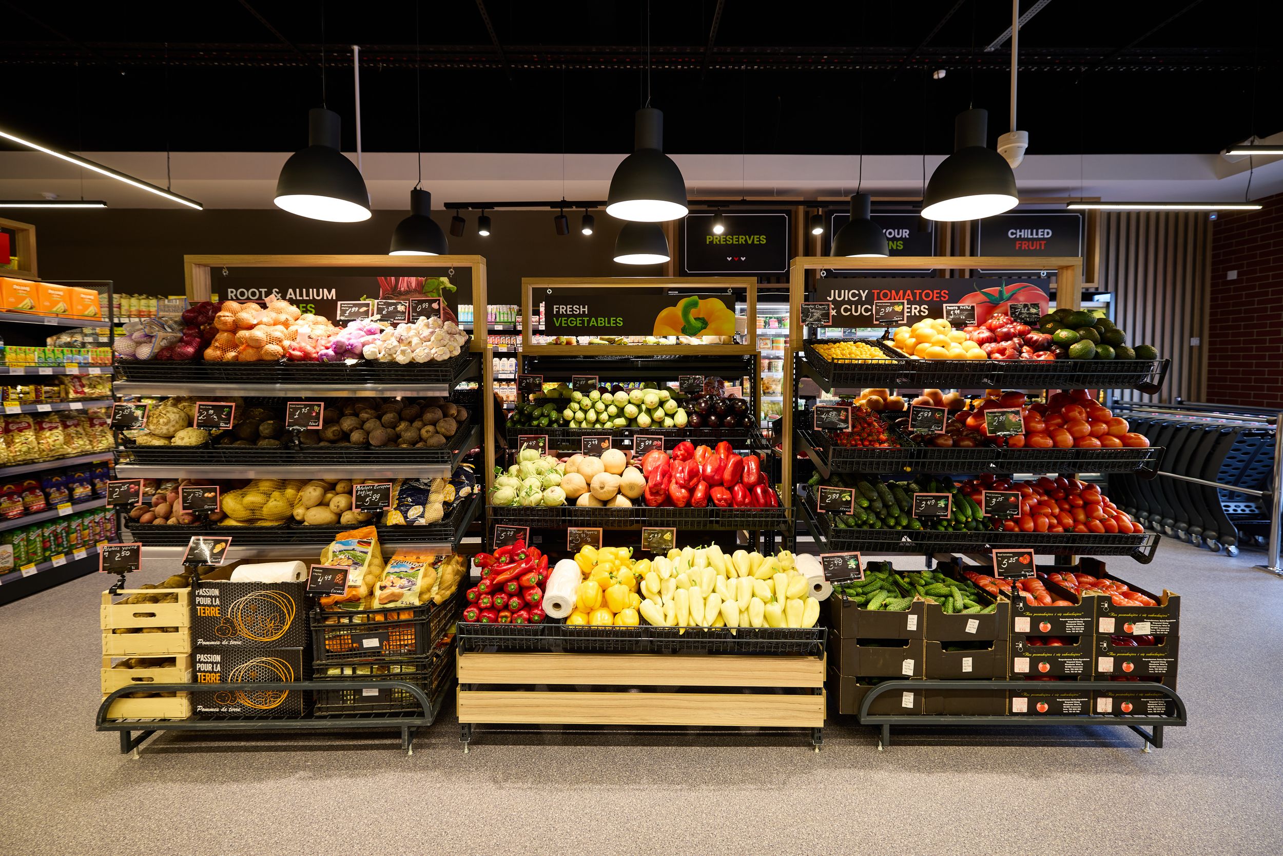 Wide view of grocery store produce section with colorful fruit and vegetable displays.