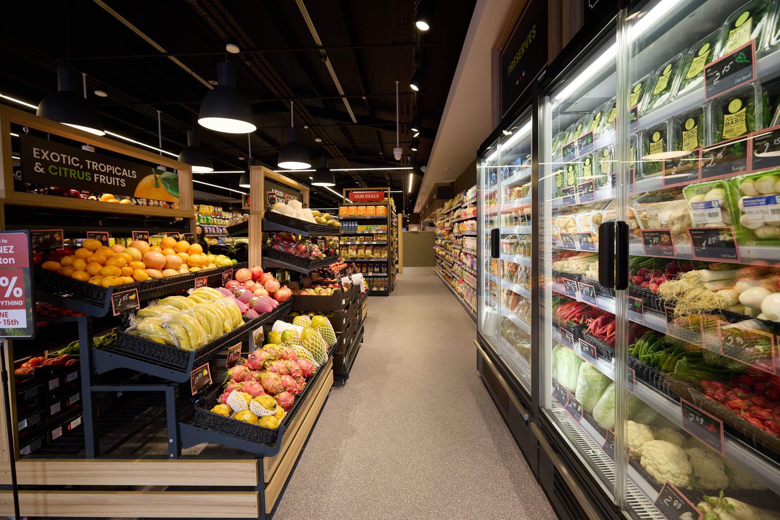 Panoramic view of supermarket produce department with fresh fruits and vegetables.