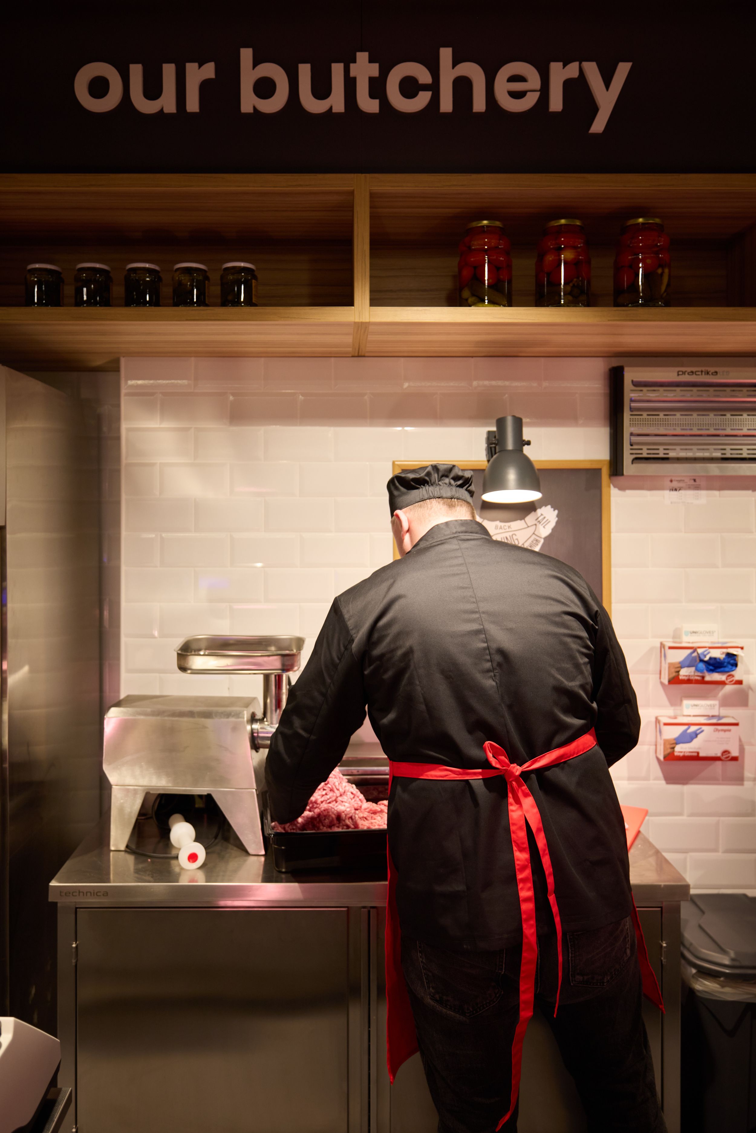 Butchers working behind counter in supermarket meat department.