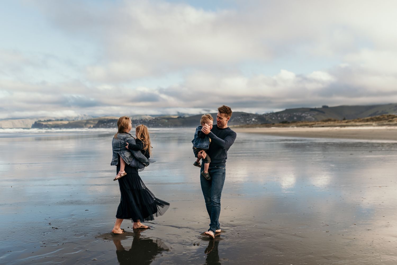 Family walking along a misty beach shoreline at sunset with mountains in the background in Christchurch.