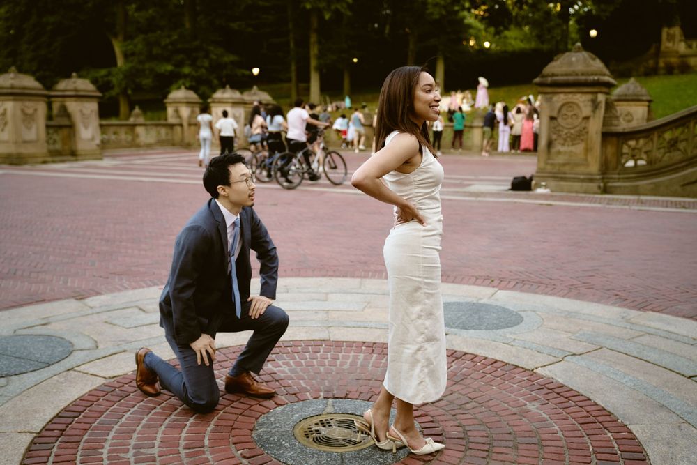A romantic proposal moment on the iconic Bethesda Terrace in Central Park during a beautiful summer day. Surprise engagement in central park