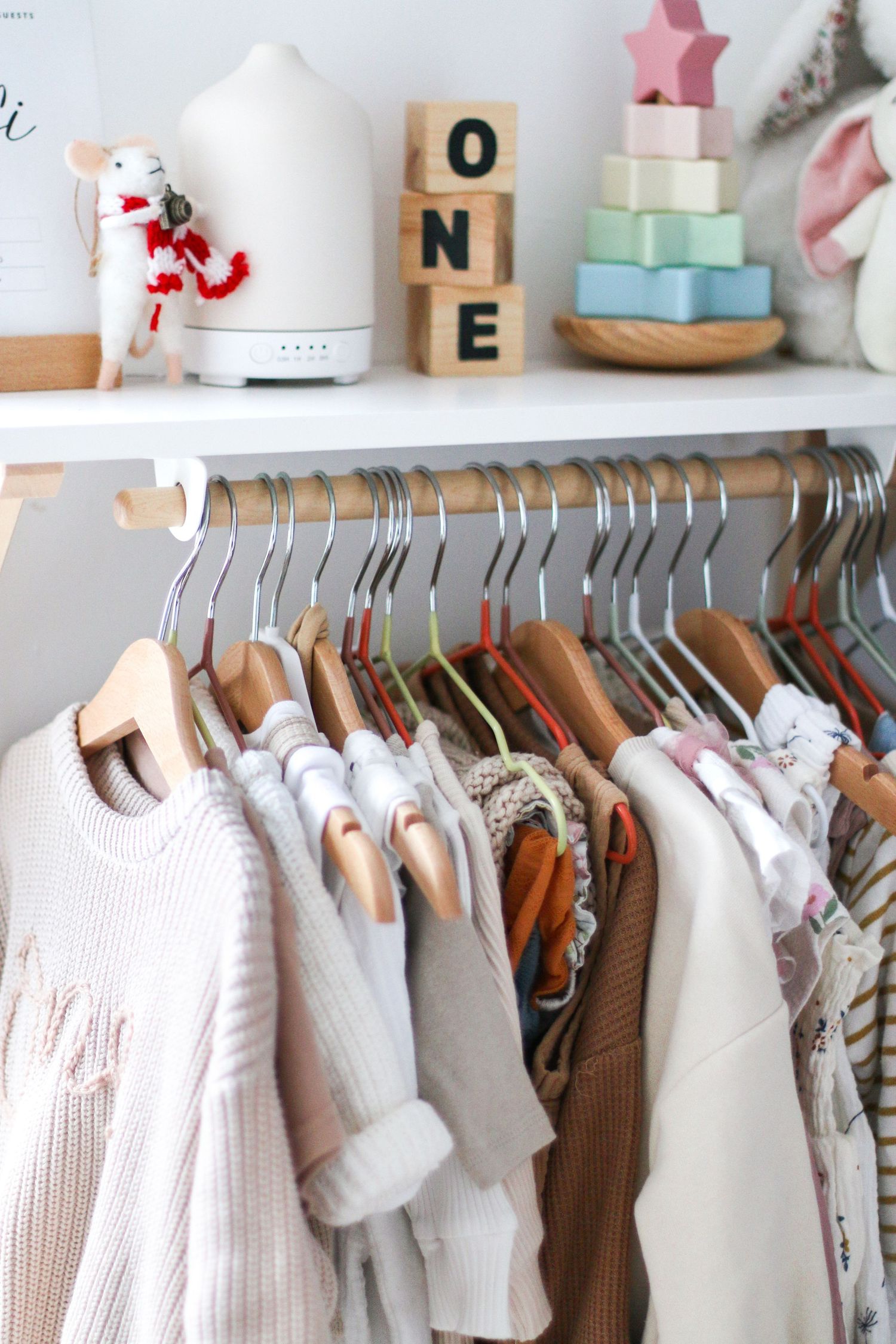 A clothes rail displays an organised collection of baby clothes in soft neutral colours like white, beige during newborn shoot in Nottingham