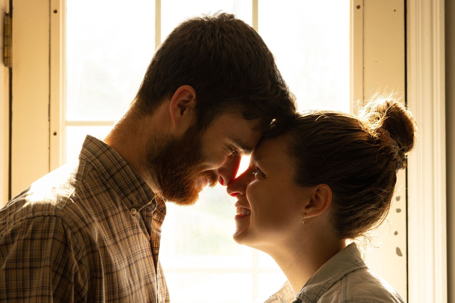 A silhouetted couple embraces in a warm, backlit hallway creating a romantic atmosphere.