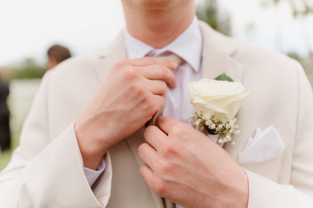 Wedding party members adjusting boutonnieres and preparing formal attire outdoors.