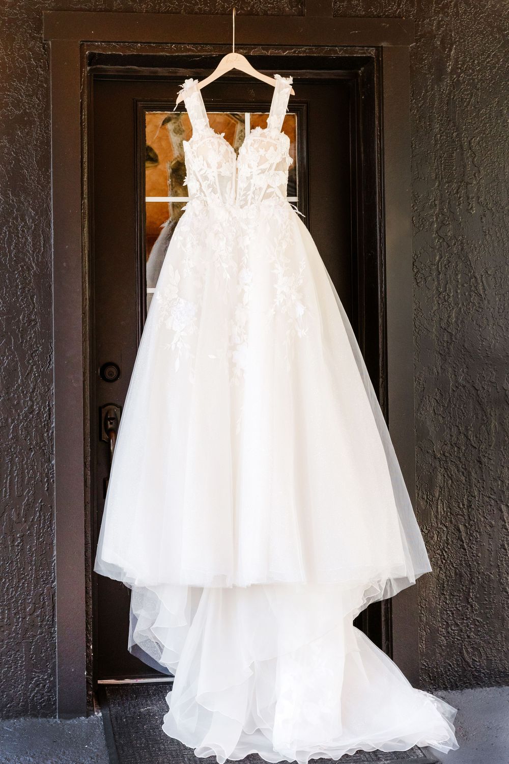 A sequence of photos showing a white wedding dress hanging on display against a dark textured wall.