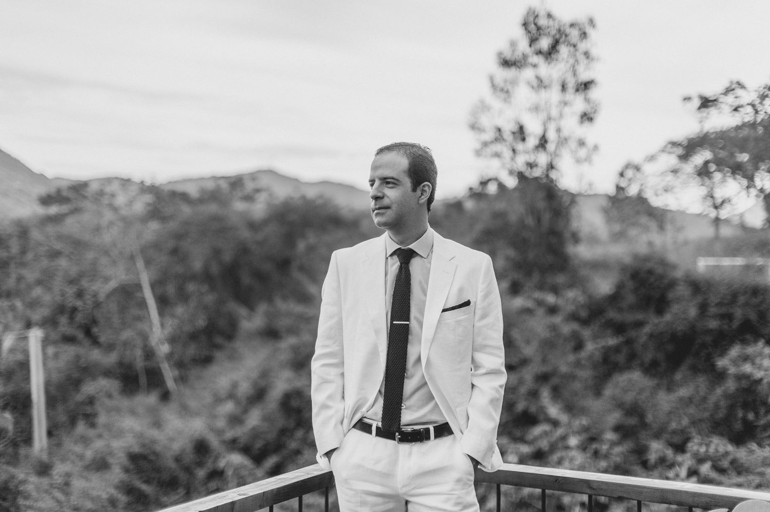 Group of groomsmen in light colored suits and dark ties walking on a grassy path at an outdoor wedding ceremony setting.