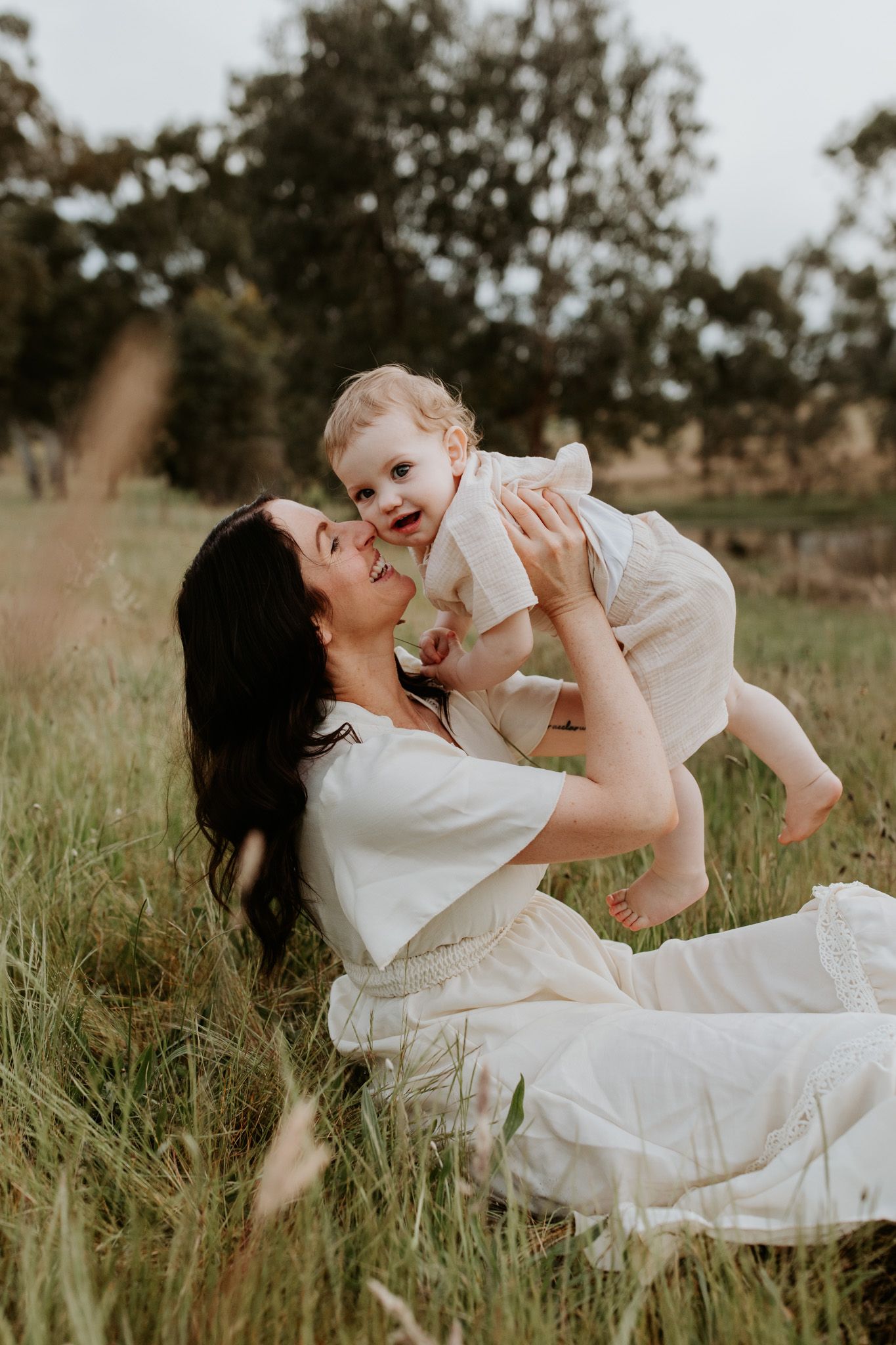 A mother and child laughing together in a field of long grass in the Adelaide Hills being captured by Lauren Lunn Photography