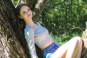 A casual outdoor portrait taken in a forest with natural lighting and greenery.