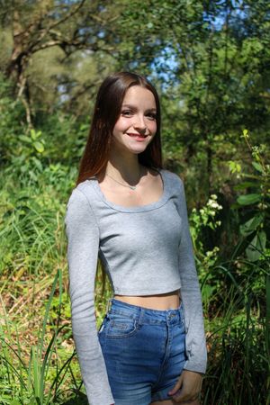 Summer fashion portrait featuring grey top and jeans in natural forest setting.