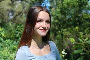 Cheerful outdoor portrait with sunlit forest background.