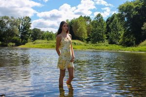 A scenic riverside photo shows someone standing in the water with lush greenery and blue sky in the background.