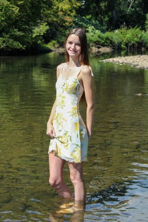A person enjoys a summer day while standing in shallow lake waters wearing a floral outfit.