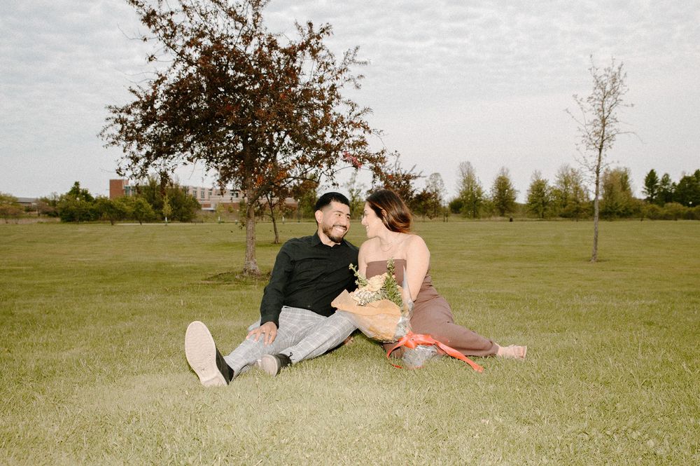 Romantic couple playfully lounges together on a grassy field during a sunny afternoon.