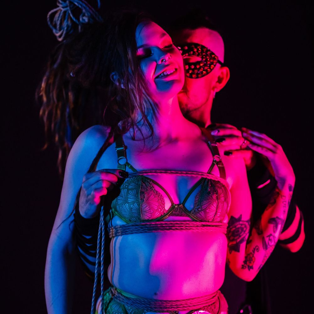 Abstract nightclub photo with neon pink and blue lighting creating dramatic silhouettes against a dark background.
