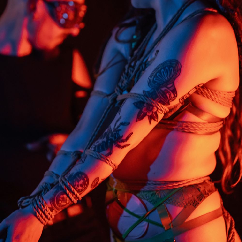 Close-up of tattooed skin illuminated by dramatic red and blue lighting creating an artistic contrast.
