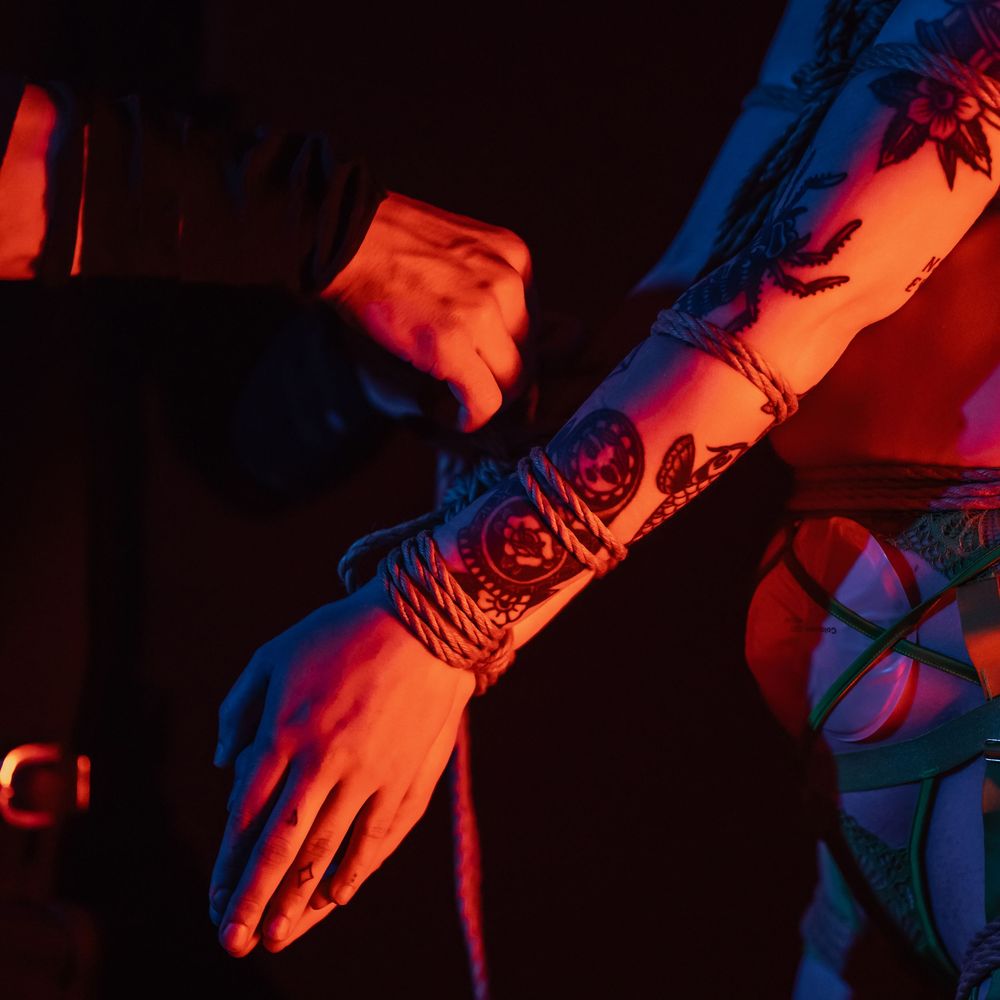 Electronic dance music party with blue and red neon lights illuminating hands and arms in motion.