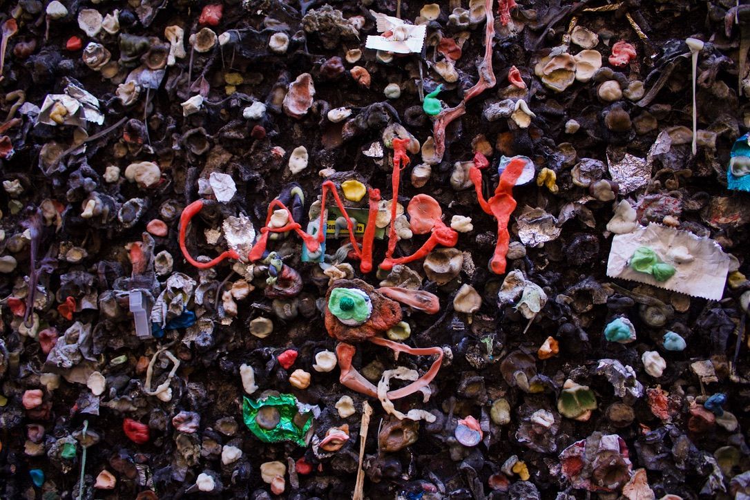 Close-up view of a wall covered in colorful gum pieces creating a unique textural pattern.