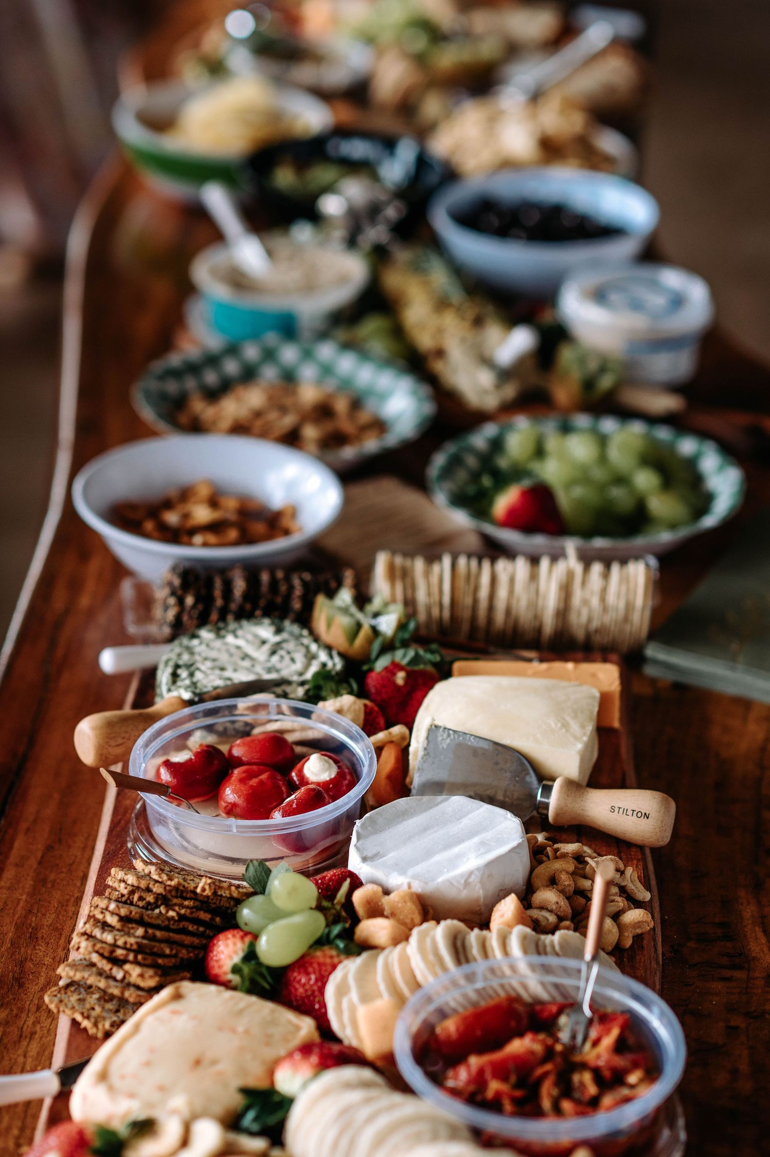 Close-up view of a rustic charcuterie board featuring bread, cheese, nuts, grapes, and meats spread across a wooden table.