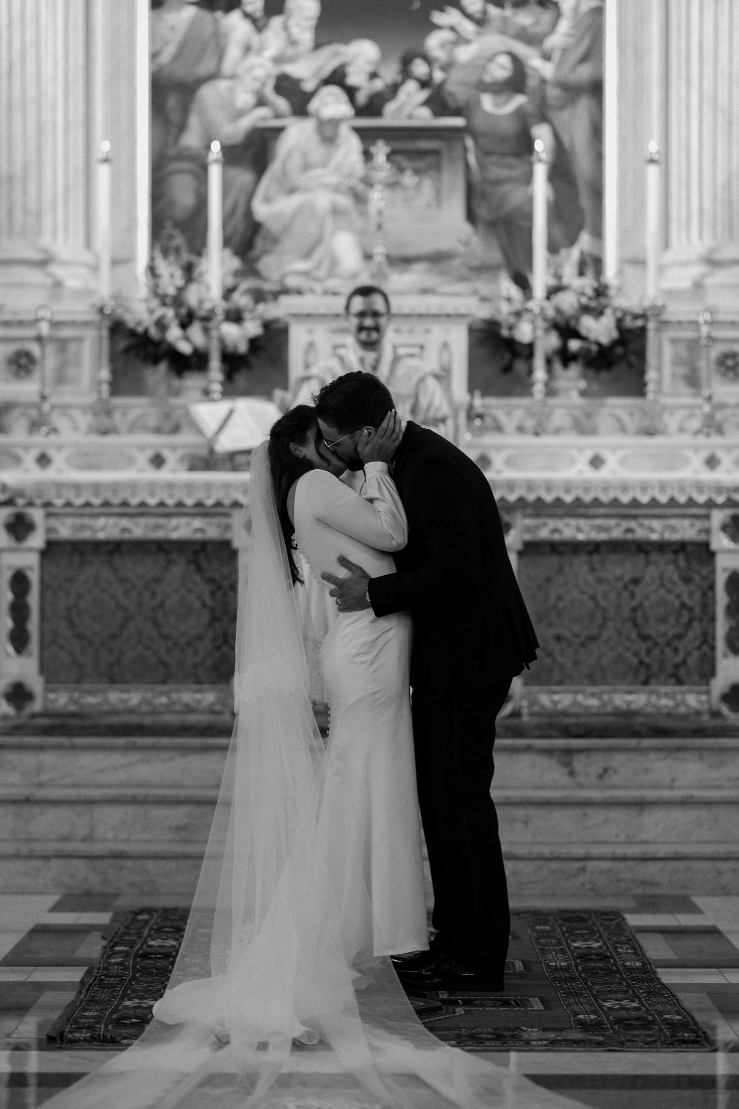 A black and white wedding portrait showing an intimate moment in a grand church setting.