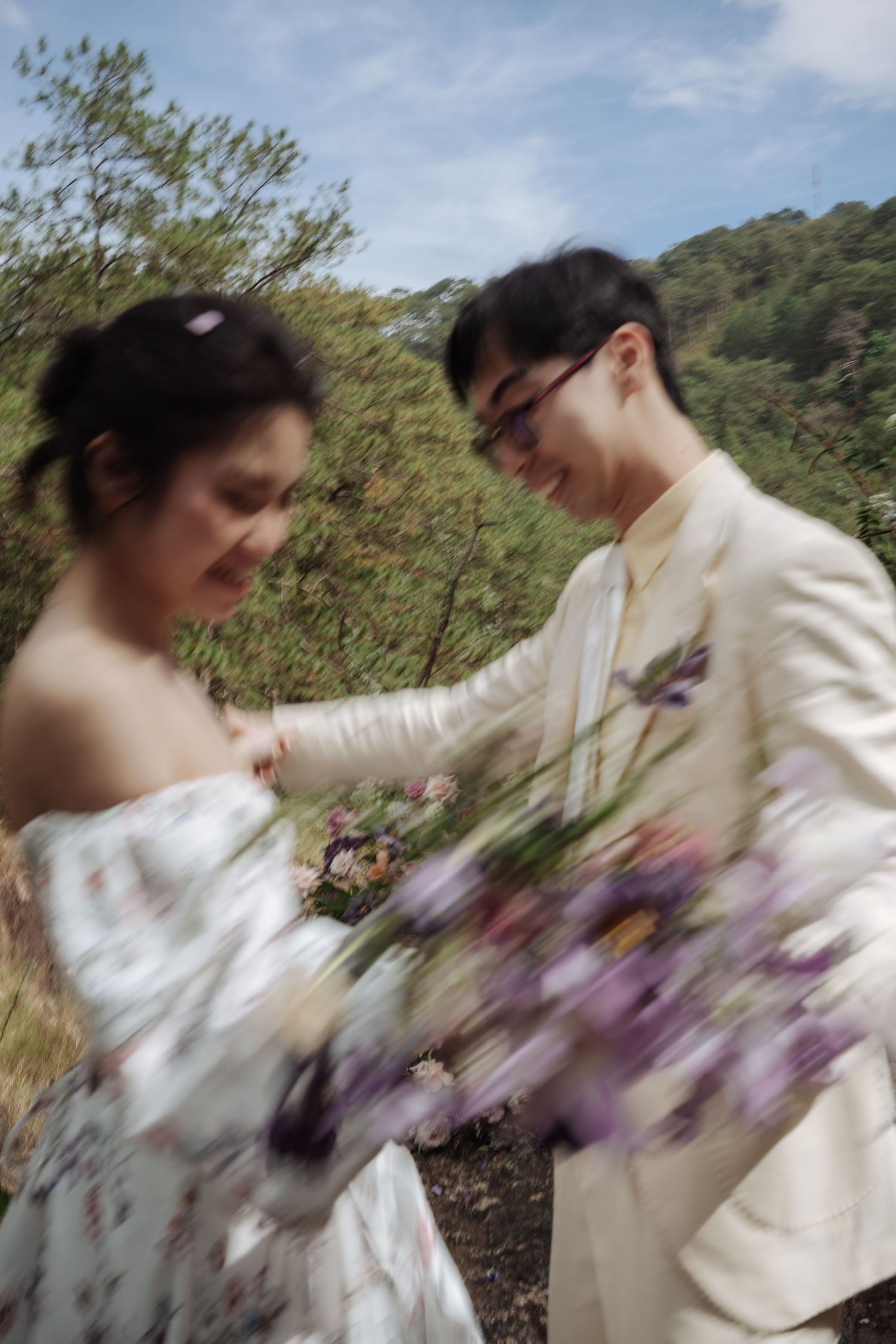 Bride and groom share a tender moment with wildflower bouquet in a lush outdoor setting.