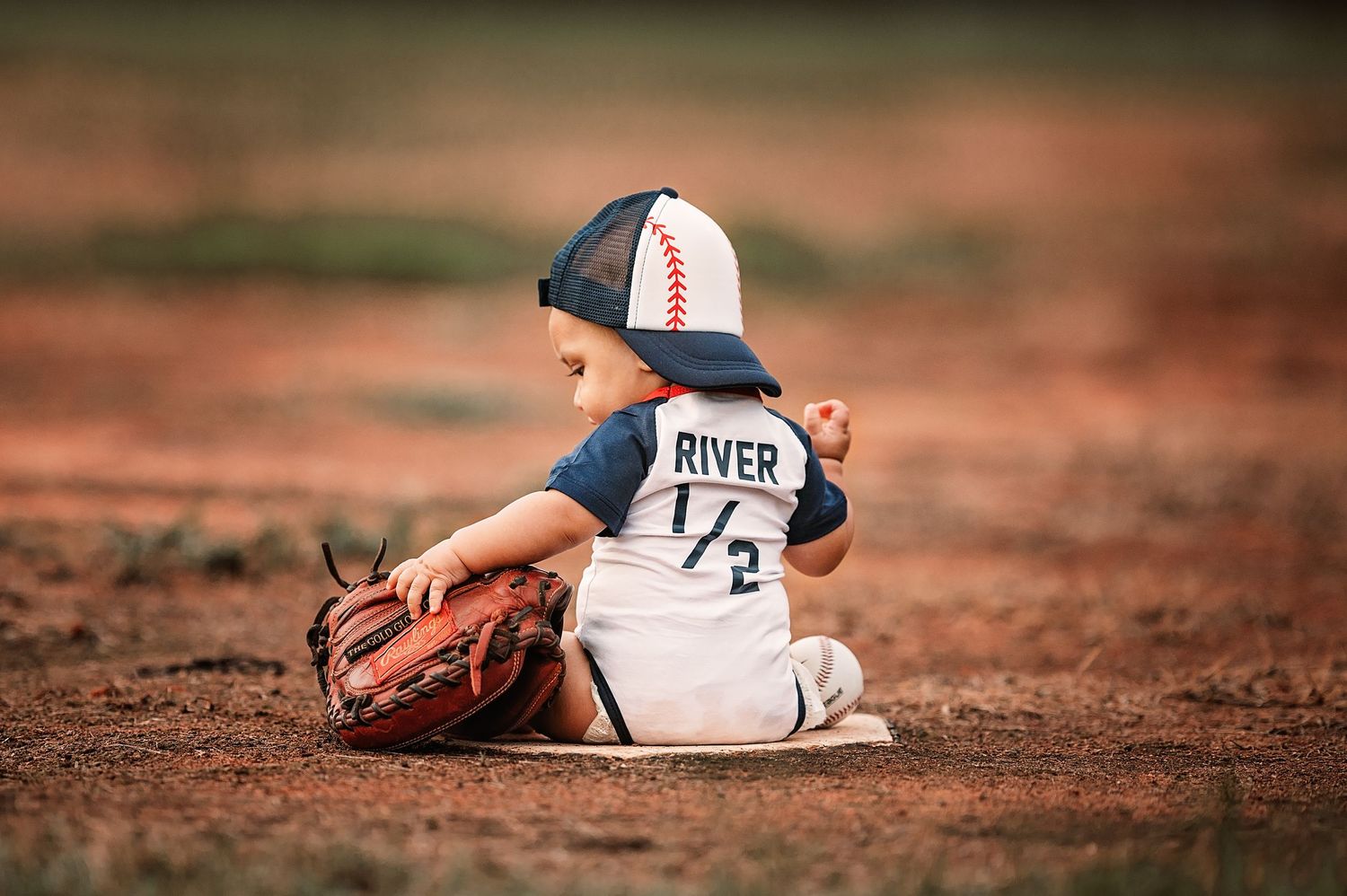Player lying on dusty baseball field in white uniform making sliding play motion.
