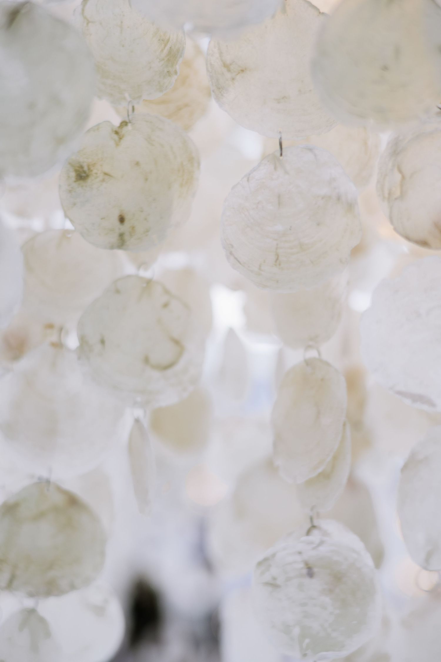 Close-up of translucent white capiz shell chandelier discs creating a delicate, luminous wedding decoration.