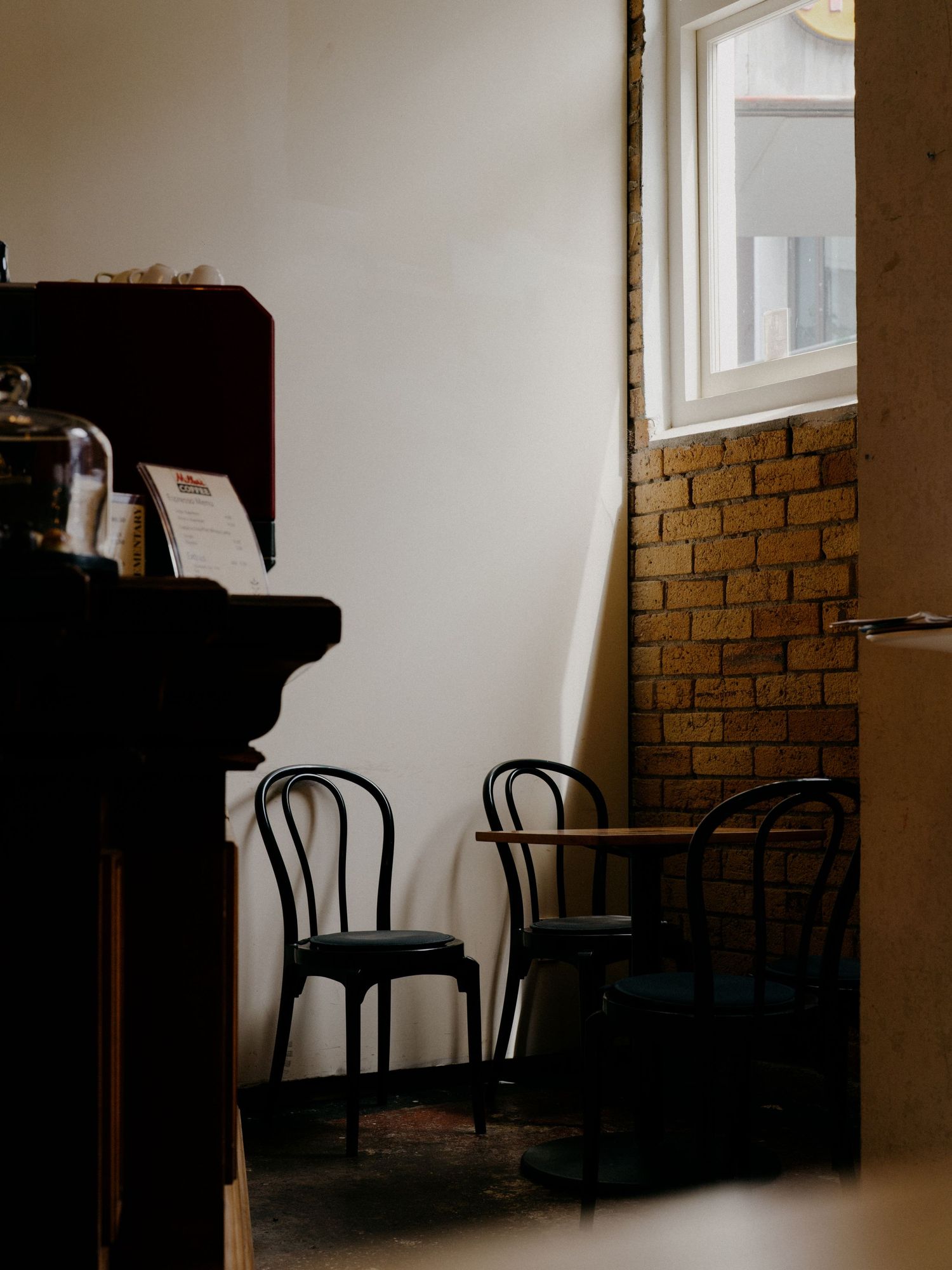Minimalist interior with bentwood chairs and exposed brick wall in warm light.