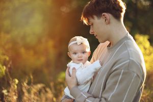 Family enjoying a tender moment together in a golden sunlit field at sunset.