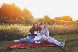A series of candid family photos captured at sunset showing intimate moments on a red plaid blanket.