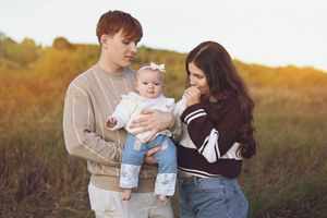 Family enjoying a tender moment together in a sunlit field during golden hour.