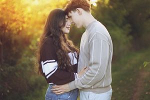 Couple sharing an intimate moment in a sunlit outdoor setting with natural bokeh effects.
