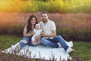 A family sitting on blanket in blooming lavender field at sunset.