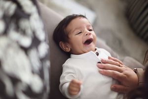 A series of photos showing a newborn baby being gently held and supported during a professional photography session.
