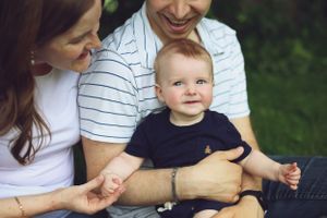 A young family sharing a tender moment outdoors in summer.
