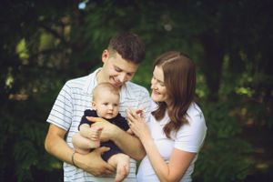 A young family shares a tender moment together outdoors with their baby in a natural setting.