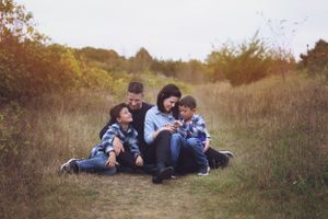 A family sitting together in a golden autumn field at sunset.