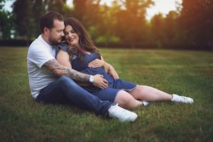 A couple relaxes together on green grass during sunset creating a romantic outdoor moment.