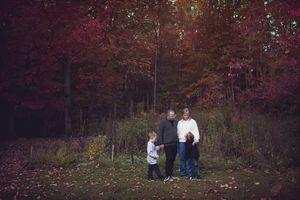 People enjoying a fall day in the woods surrounded by red autumn foliage.