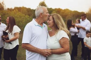 An affectionate mature couple in white sharing a tender moment outdoors.