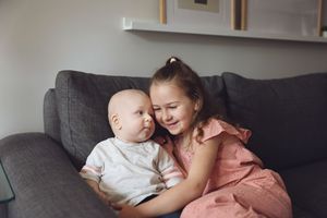 A sweet moment of laughter and bonding between two people sitting together on a dark gray couch.