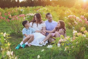 A family sitting together in a blooming flower garden during sunset.
