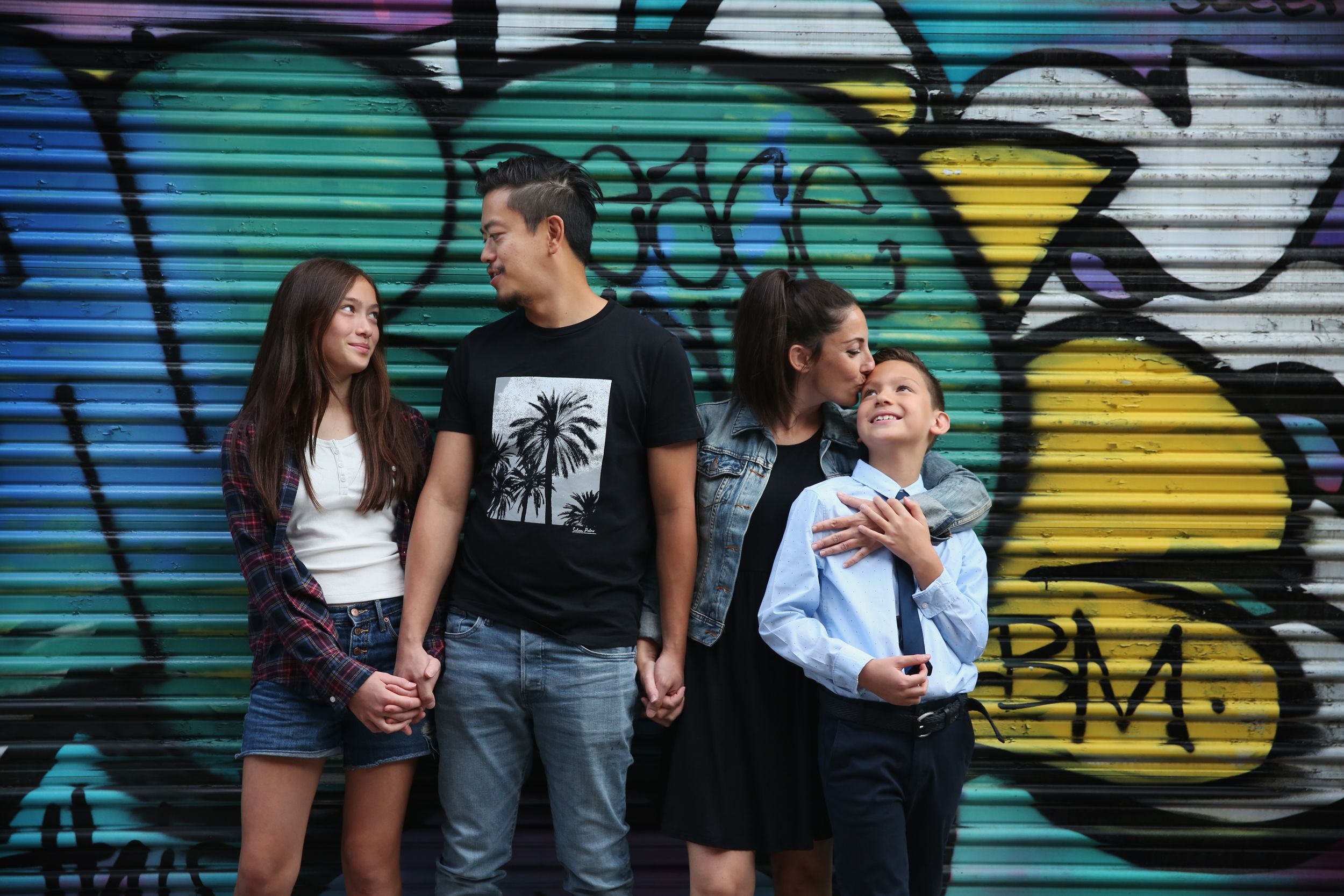 Group photo against colorful graffiti wall showcases casual urban style.