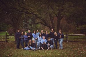 A group photo session in a park during autumn with fallen leaves scattered on the ground.
