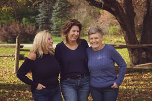 A group poses together for outdoor autumn family portraits in a park with fall foliage in the background.