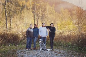 A group of people and their dog stand together on a trail surrounded by autumn foliage in golden afternoon light.