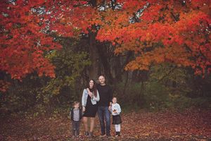People gathered under vibrant red maple trees during peak fall foliage season.