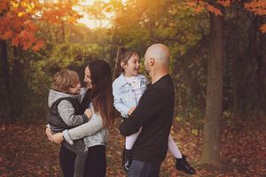 A romantic autumn photo session in a wooded park during golden hour with warm orange sunlight filtering through trees.