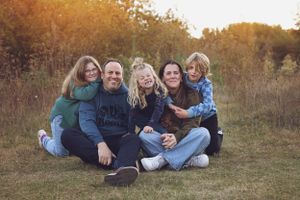 A casual group photo of friends sitting together in a field during golden hour.